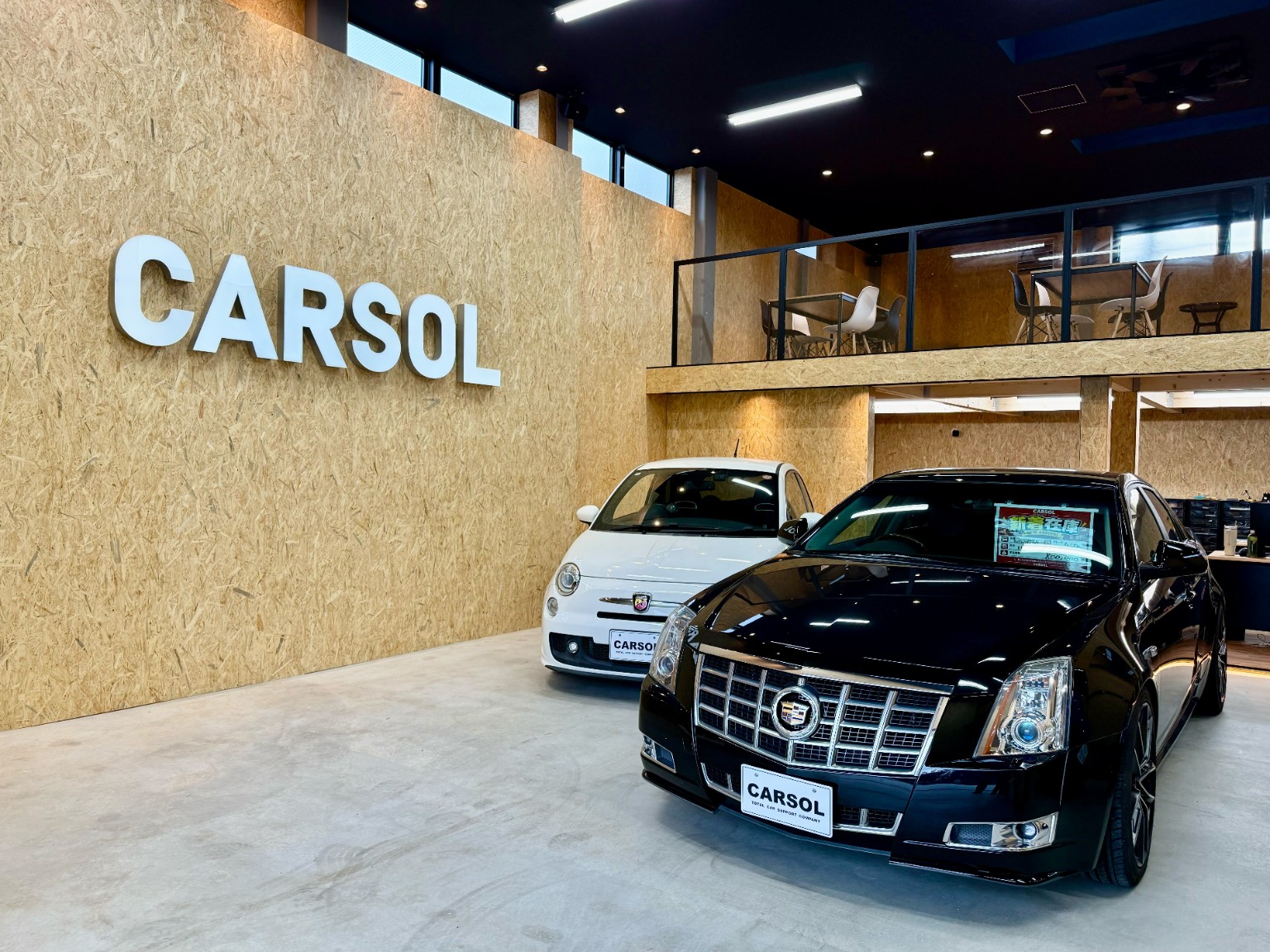 CARSOL横浜店のショールーム。黒いキャデラックと白い車が並ぶ。